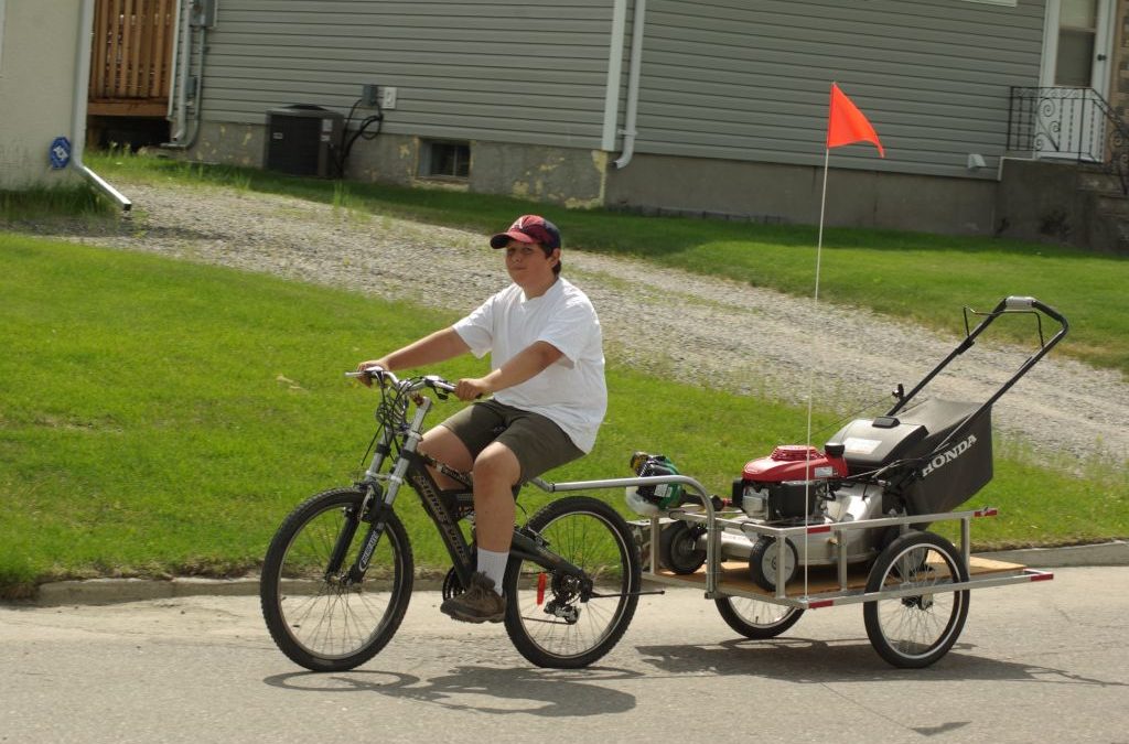 Thompson youth pushes pedals and a mower