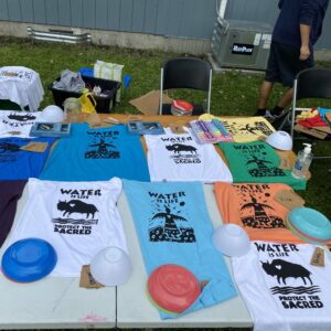 A collection of colourful shirts drying with various 'Water is Life' imagery. 