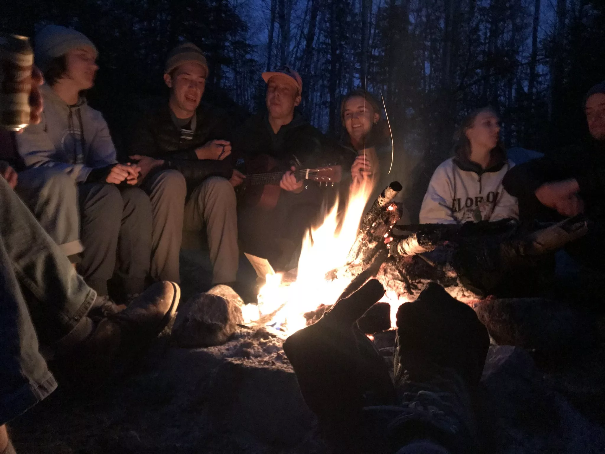 group of teens sitting around a campfire