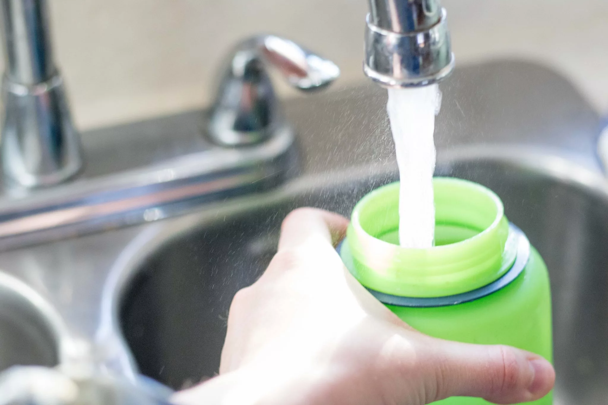 drinking container being filled with water from a faucet