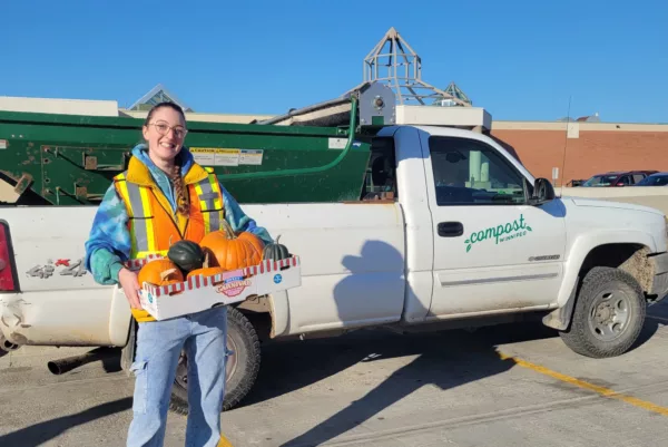 compost winnipeg volunteer carrying a box of old pumpkins