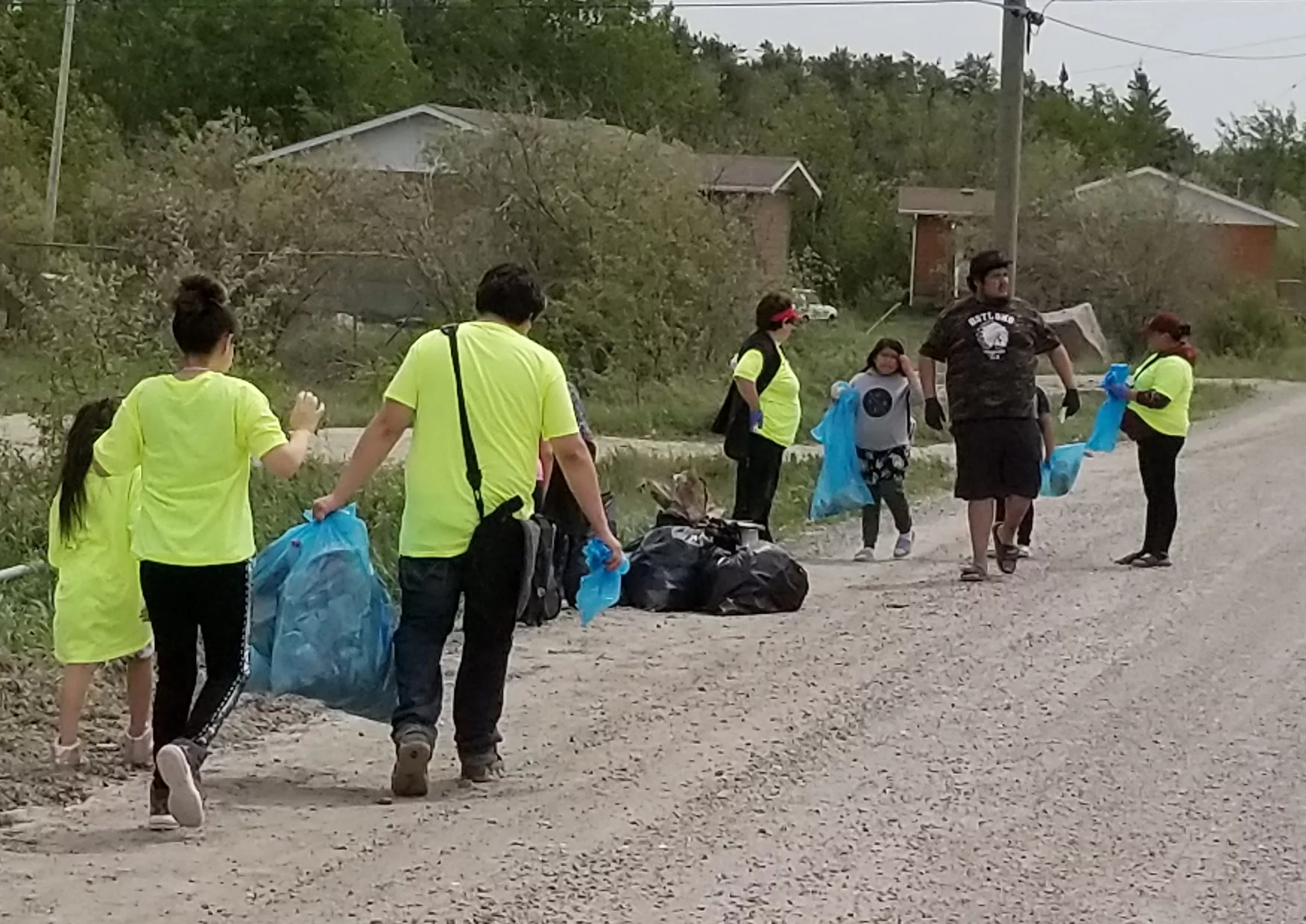 bloodvein community cleanup volunteers wearing bright shirts and carrying bags