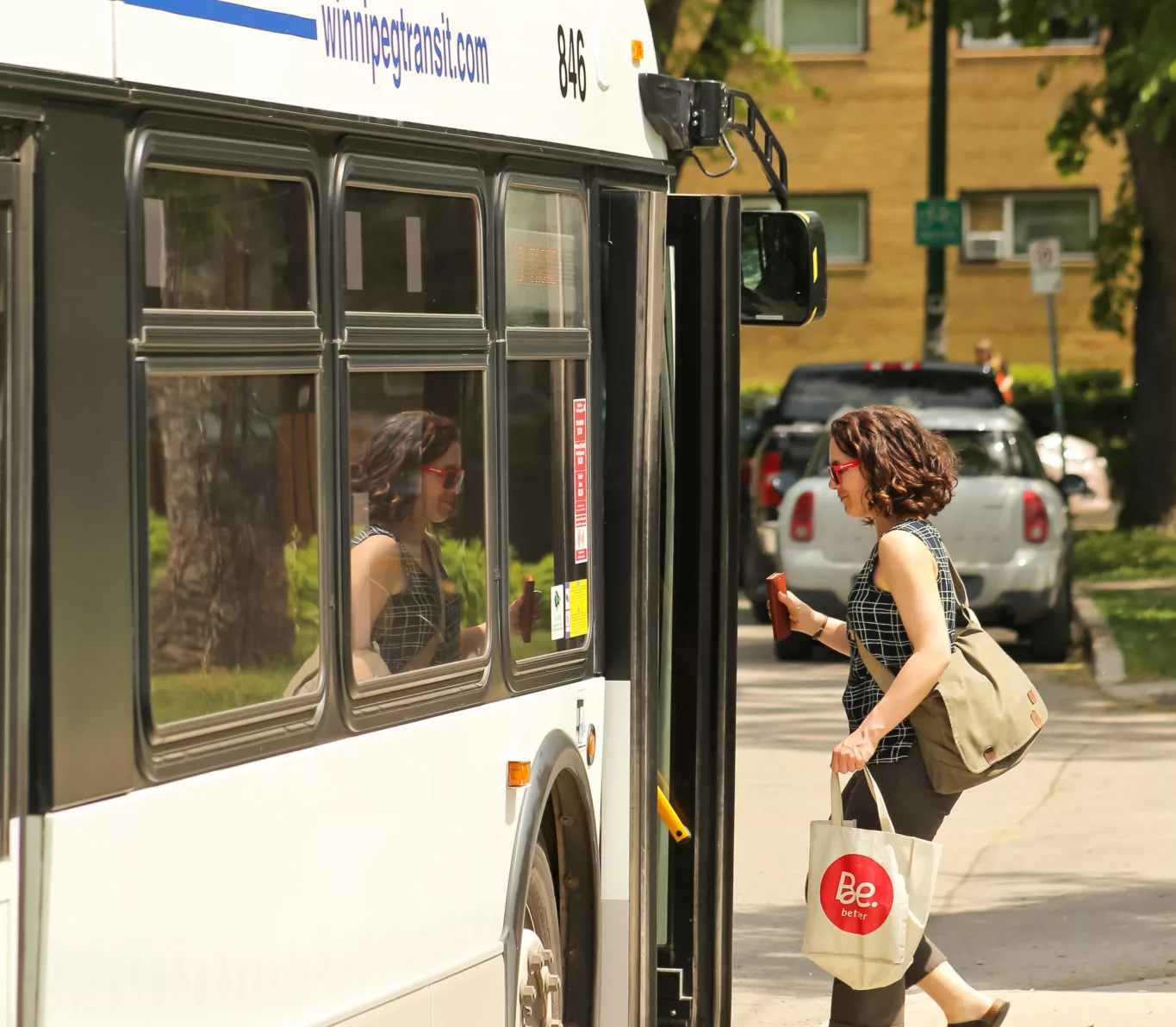 go manitoba is for everyone - woman boarding bus holding travel mug