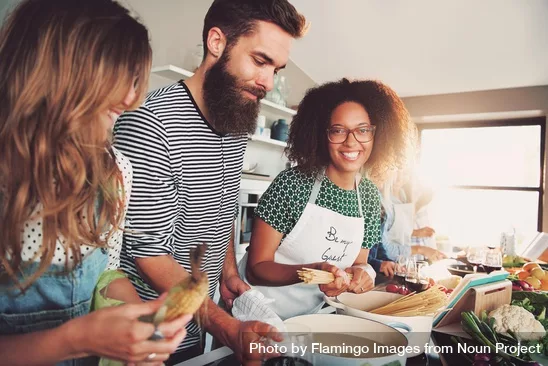 three young people preparing food together in a kitchen